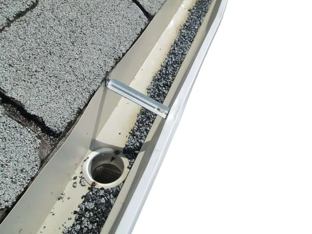 Asphalt granules clogging gutter after hail damage.